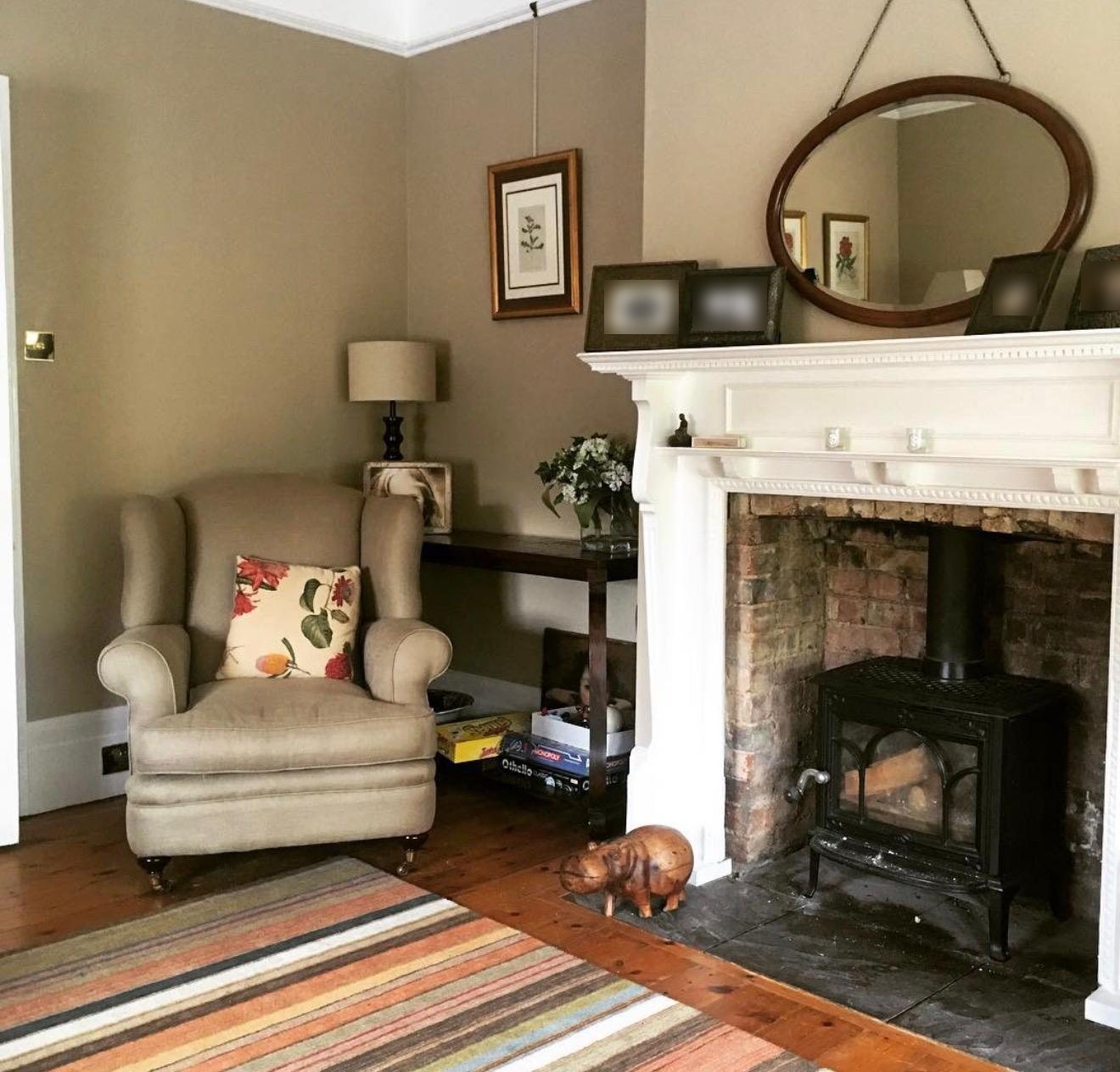 Sitting room with a linen wing chair and wood burner